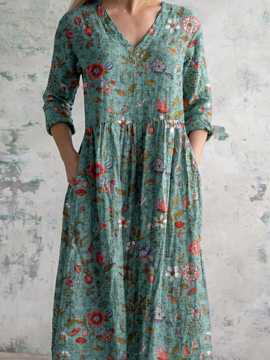 3XL - A woman wearing a teal botanical print linen maxi dress with three-quarter sleeves, a V-neckline, and side pockets, showcasing a relaxed bohemian silhouette.