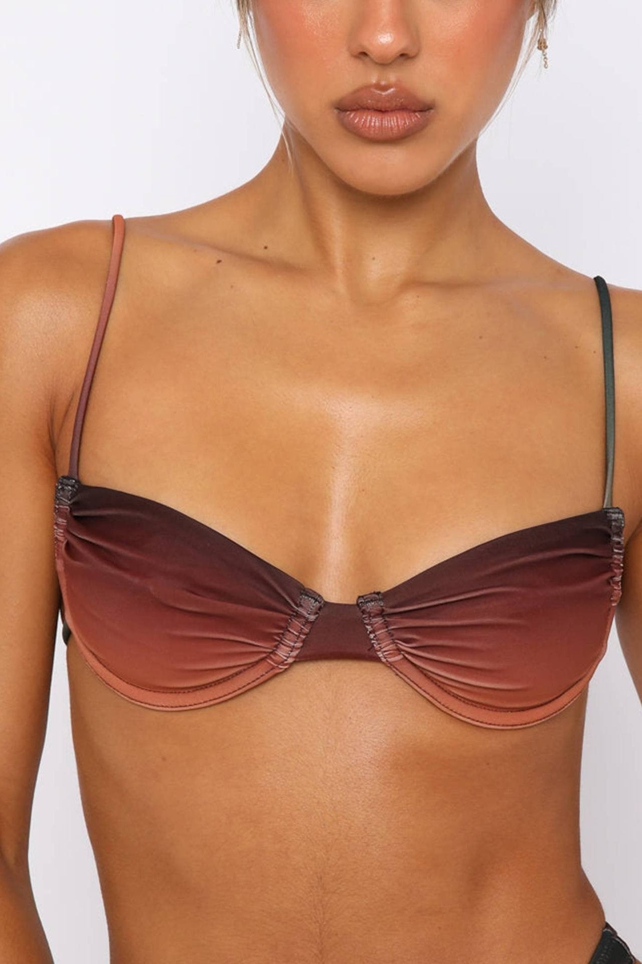 Full body shot of a woman wearing a red and orange gradient bikini set with a ruched bandeau top and high-cut bottoms.