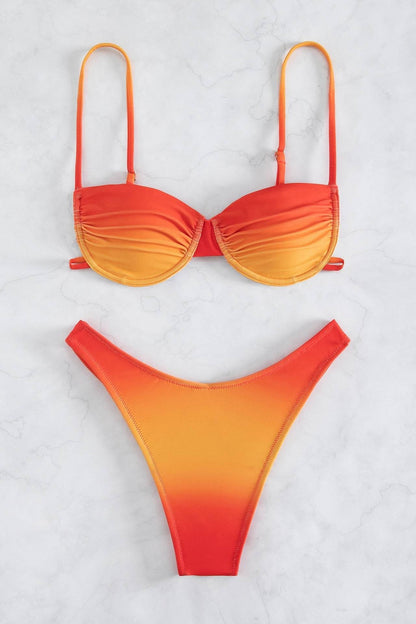 Full body shot of a woman wearing a red and orange gradient bikini set with a ruched bandeau top and high-cut bottoms.