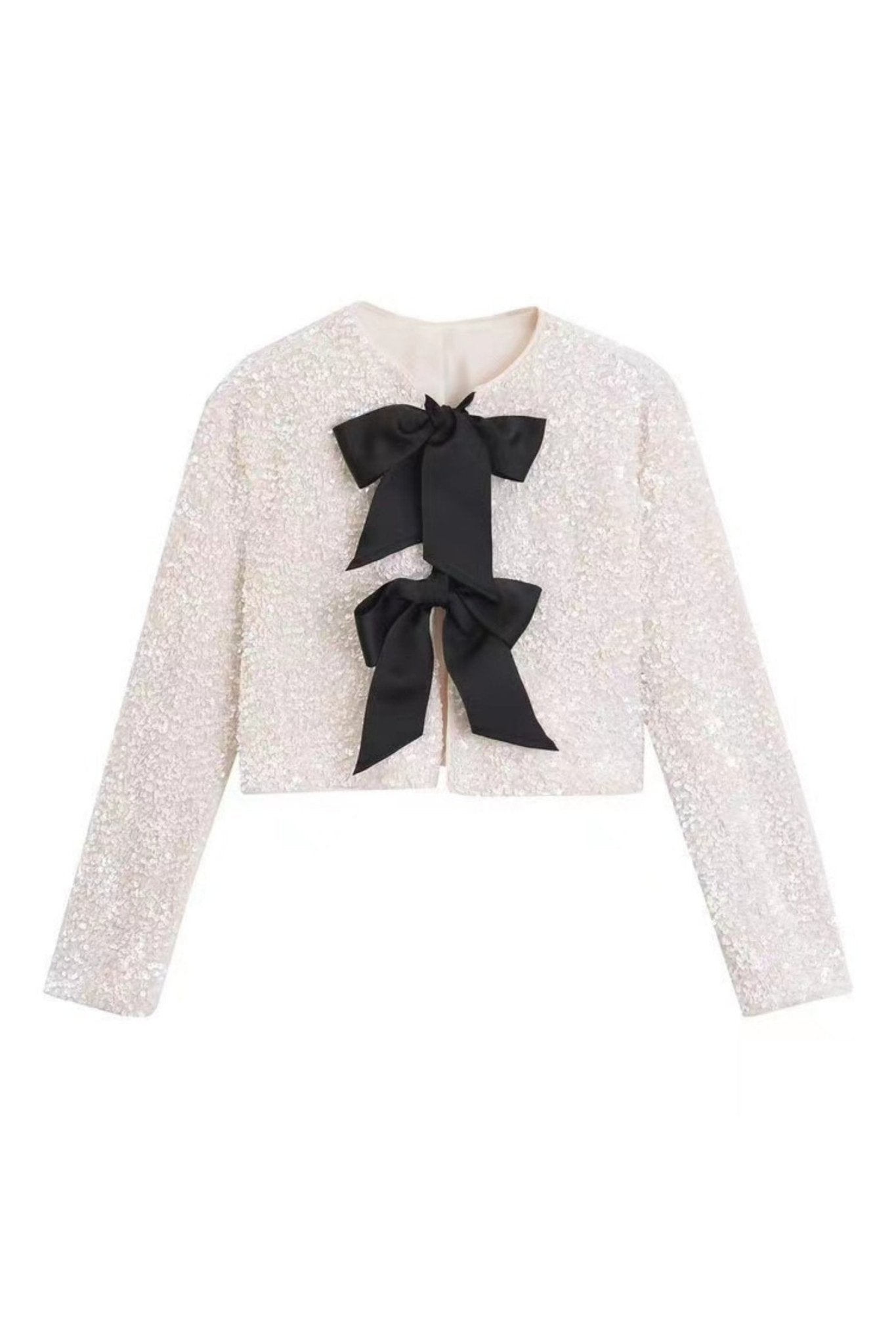White - A model wearing a black cropped jacket covered in sequins, featuring two large black bows at the front closure.