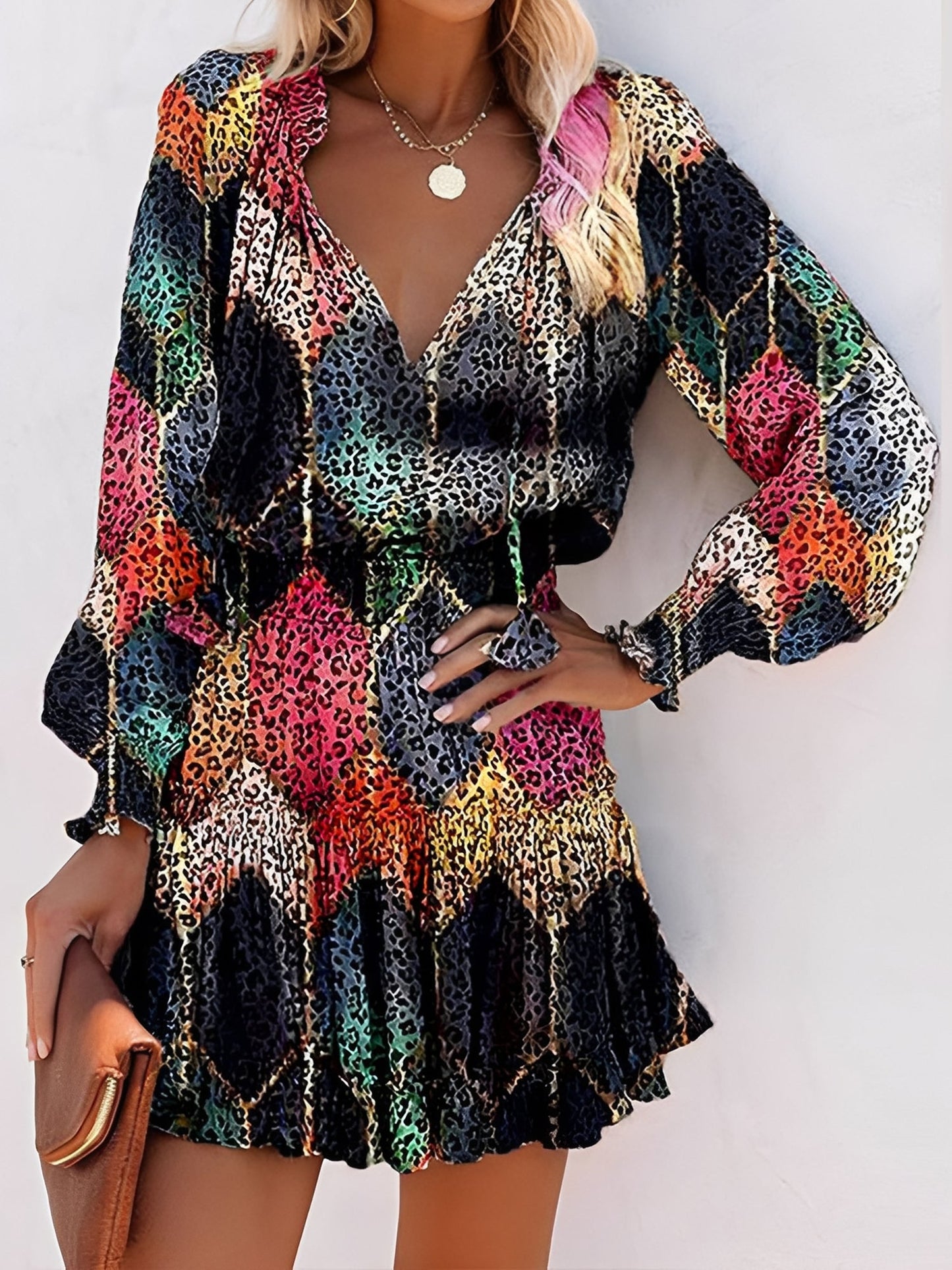 Black - Woman wearing a lightweight leopard print mini dress with long sleeves, a v-neckline with ties, a smocked waist, and a tiered ruffled skirt