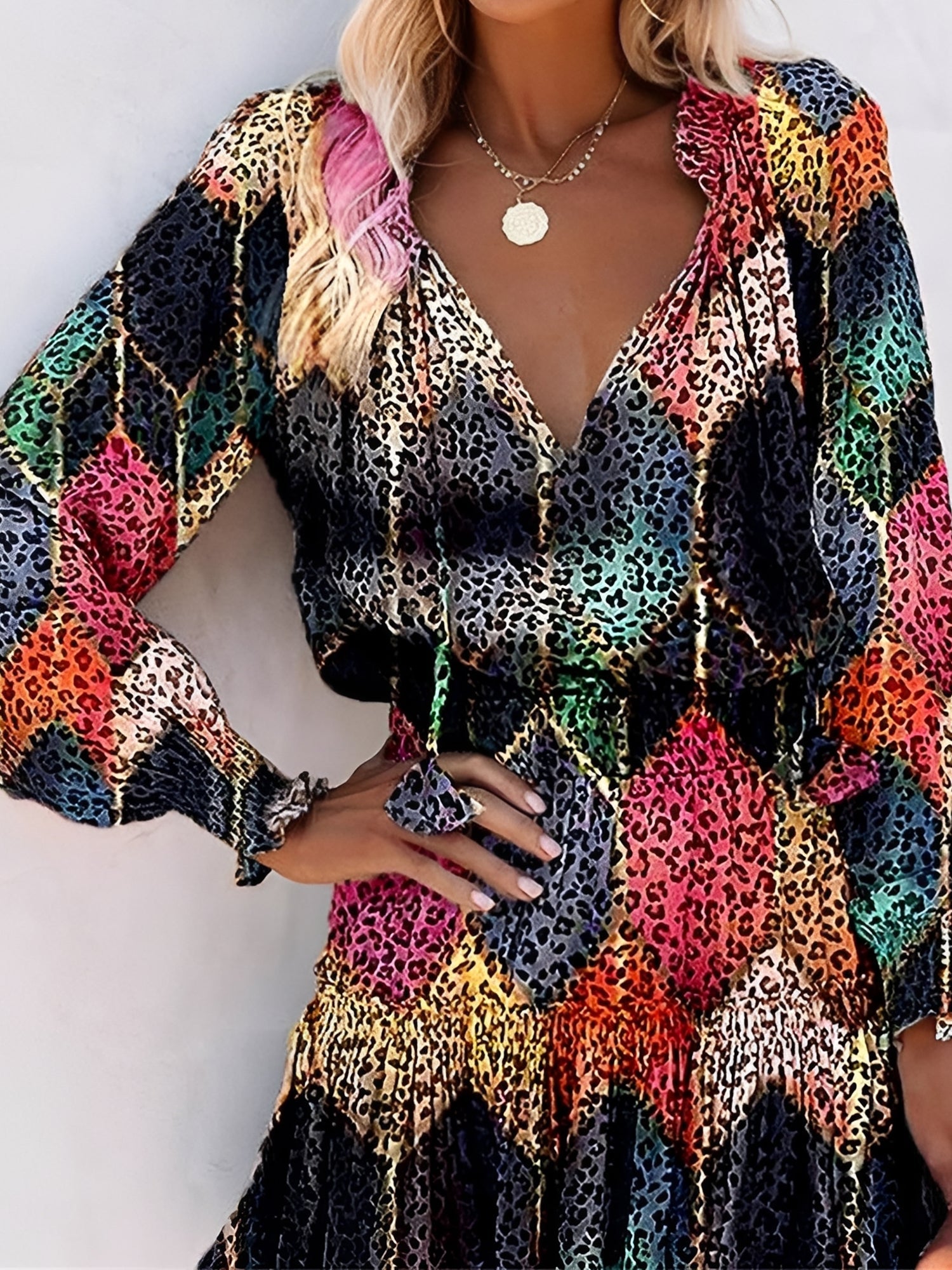 Black - Woman wearing a lightweight leopard print mini dress with long sleeves, a v-neckline with ties, a smocked waist, and a tiered ruffled skirt