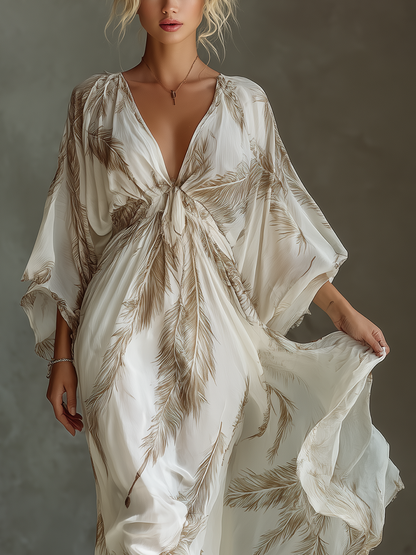 Ivory - Model walking in a flowing, semi-sheer maxi dress featuring a deep V-neckline, wide kimono sleeves, and a large-scale plume print pattern.