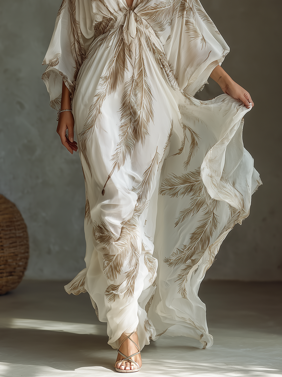 Ivory - Model walking in a flowing, semi-sheer maxi dress featuring a deep V-neckline, wide kimono sleeves, and a large-scale plume print pattern.
