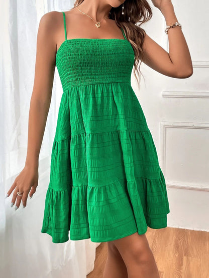 Green - Woman wearing a textured smocked bodice mini dress with spaghetti straps and a tiered skirt