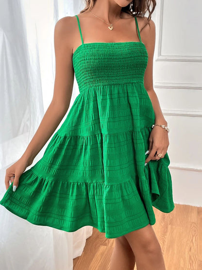 Green - Woman wearing a textured smocked bodice mini dress with spaghetti straps and a tiered skirt