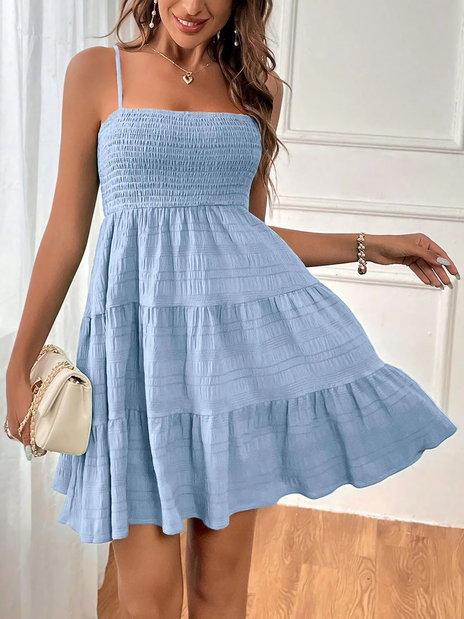 Light Blue - Woman wearing a textured smocked bodice mini dress with spaghetti straps and a tiered skirt