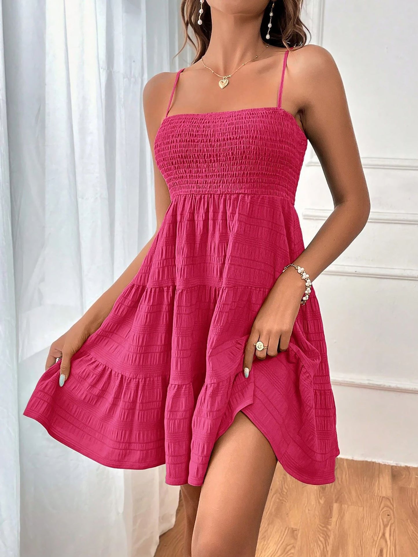 Hot Pink - Woman wearing a textured smocked bodice mini dress with spaghetti straps and a tiered skirt