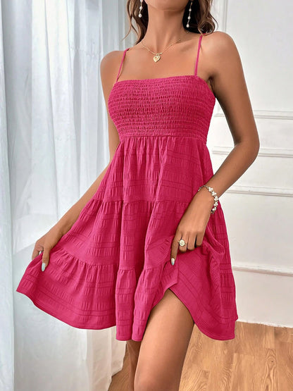 Hot Pink - Woman wearing a textured smocked bodice mini dress with spaghetti straps and a tiered skirt