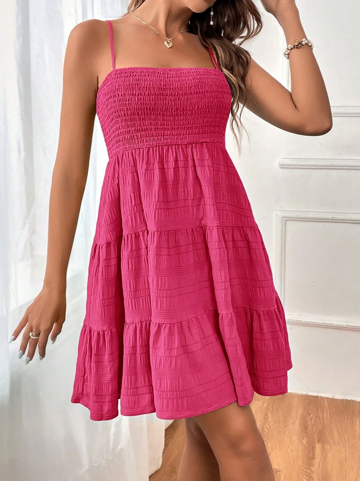 Hot Pink - Woman wearing a textured smocked bodice mini dress with spaghetti straps and a tiered skirt