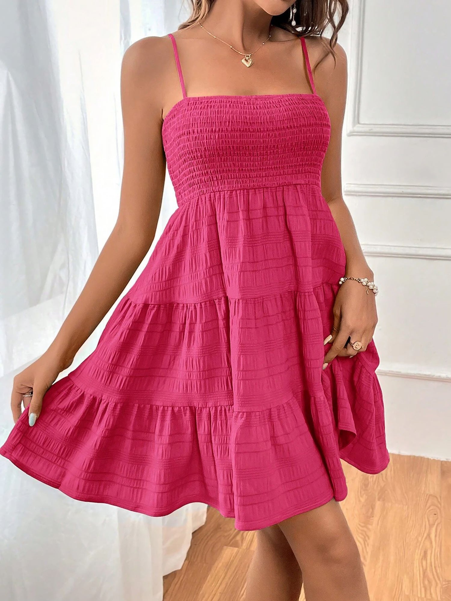 Hot Pink - Woman wearing a textured smocked bodice mini dress with spaghetti straps and a tiered skirt