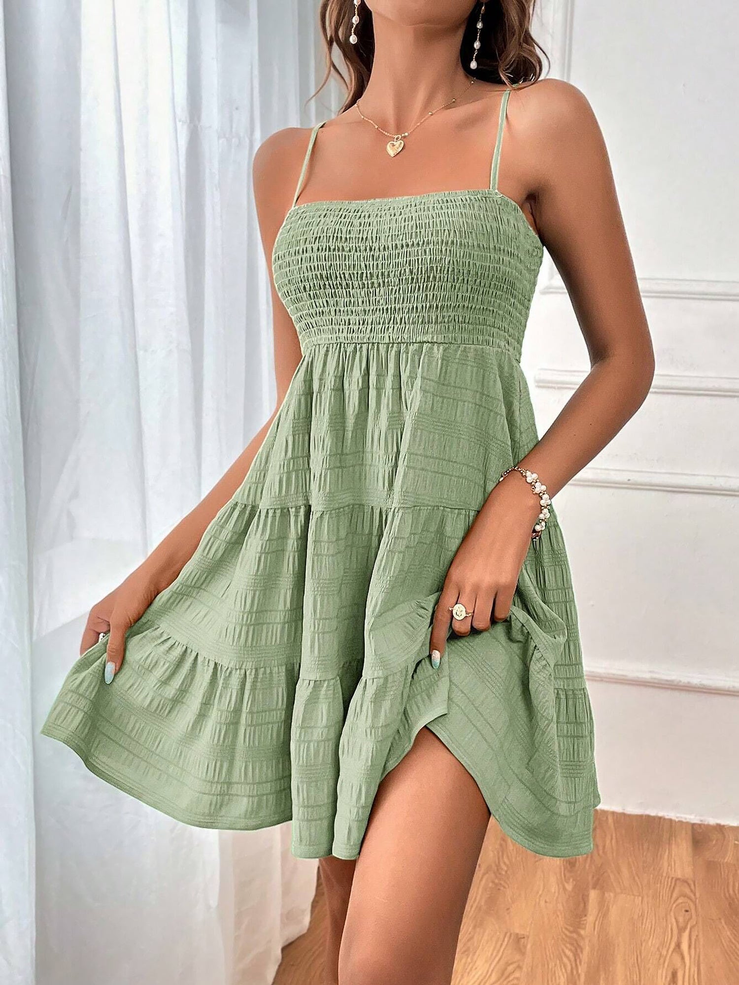 Light Green - Woman wearing a textured smocked bodice mini dress with spaghetti straps and a tiered skirt