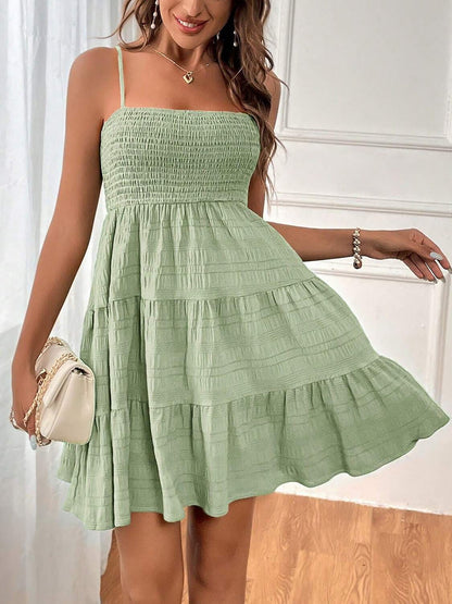 Light Green - Woman wearing a textured smocked bodice mini dress with spaghetti straps and a tiered skirt