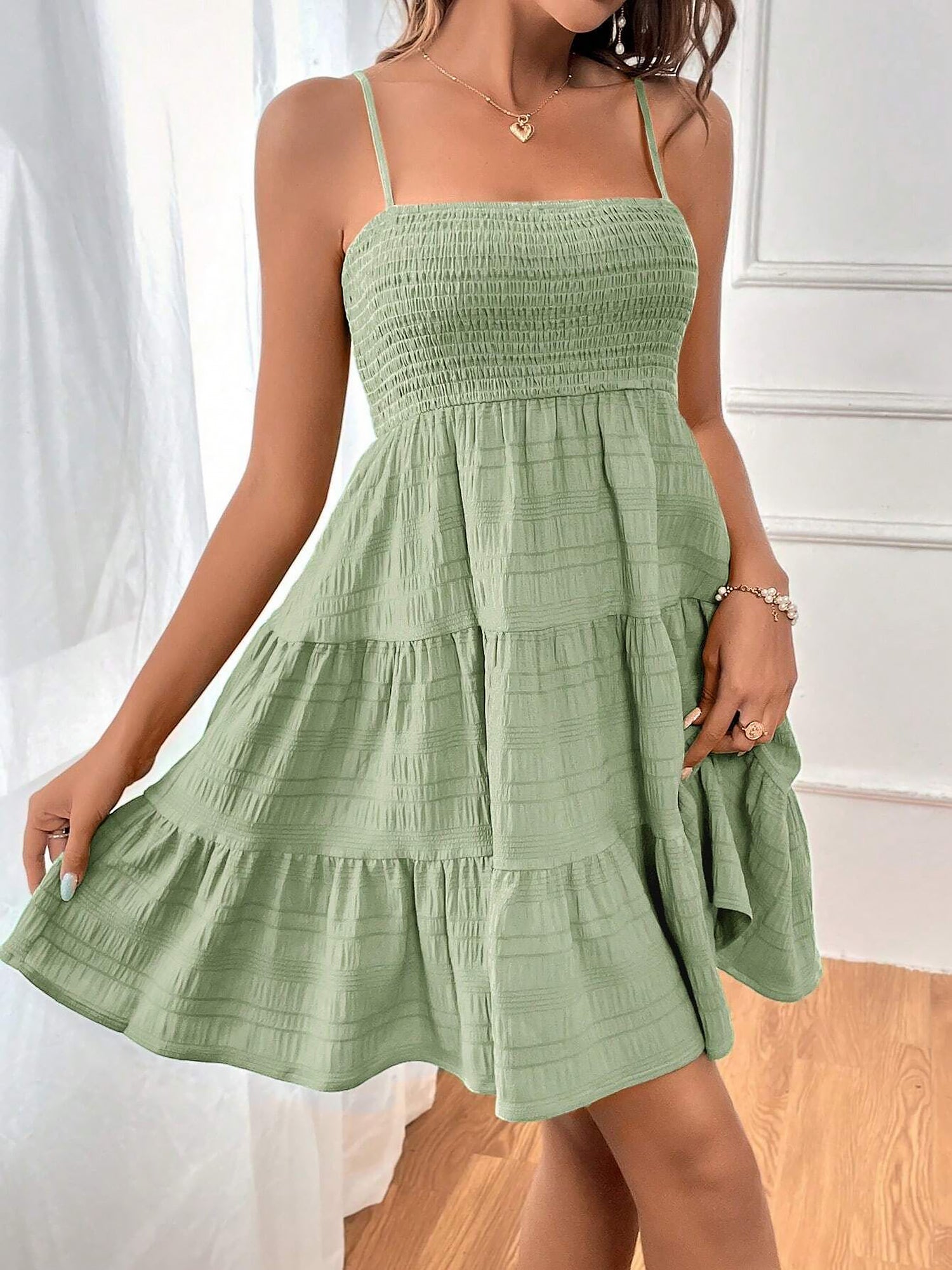 Light Green - Woman wearing a textured smocked bodice mini dress with spaghetti straps and a tiered skirt