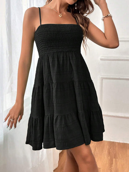 Black - Woman wearing a textured smocked bodice mini dress with spaghetti straps and a tiered skirt