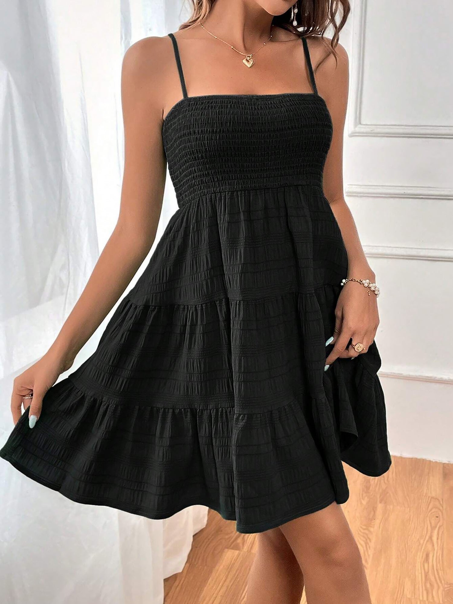 Black - Woman wearing a textured smocked bodice mini dress with spaghetti straps and a tiered skirt