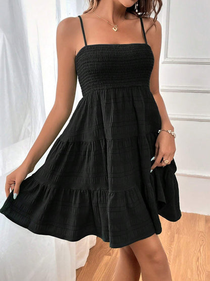 Black - Woman wearing a textured smocked bodice mini dress with spaghetti straps and a tiered skirt