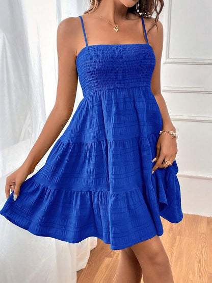 Blue - Woman wearing a textured smocked bodice mini dress with spaghetti straps and a tiered skirt