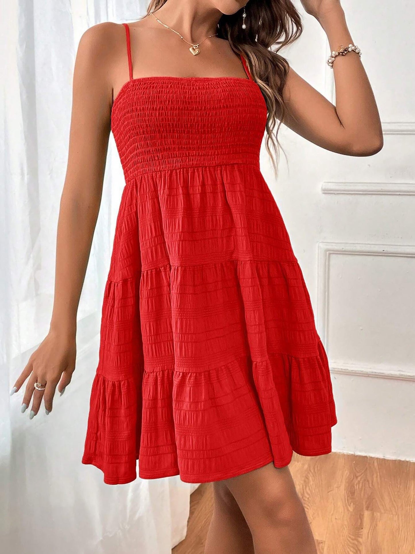 Red - Woman wearing a textured smocked bodice mini dress with spaghetti straps and a tiered skirt