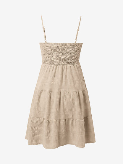 Beige - Woman wearing a textured smocked bodice mini dress with spaghetti straps and a tiered skirt
