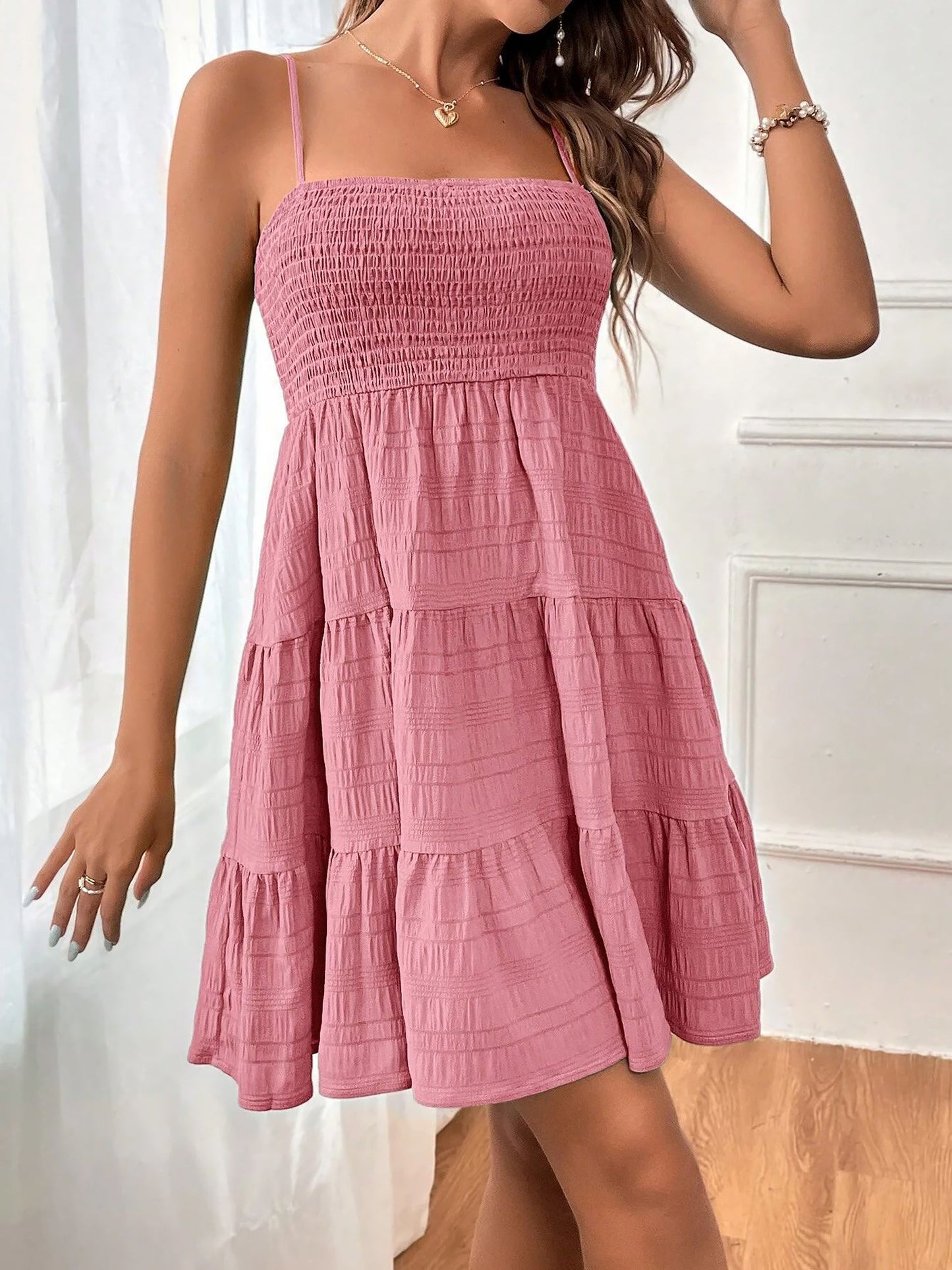 Pink - Woman wearing a textured smocked bodice mini dress with spaghetti straps and a tiered skirt