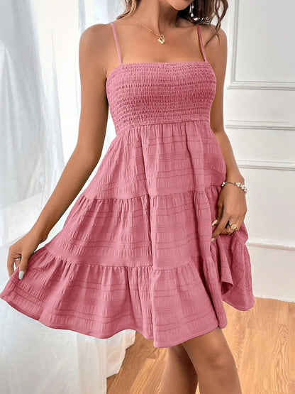 Pink - Woman wearing a textured smocked bodice mini dress with spaghetti straps and a tiered skirt