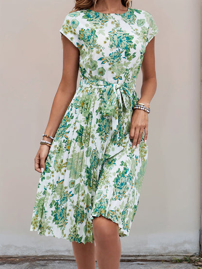 Green - Woman wearing a floral print midi dress featuring cap sleeves, a tie waist sash, and a finely pleated skirt.