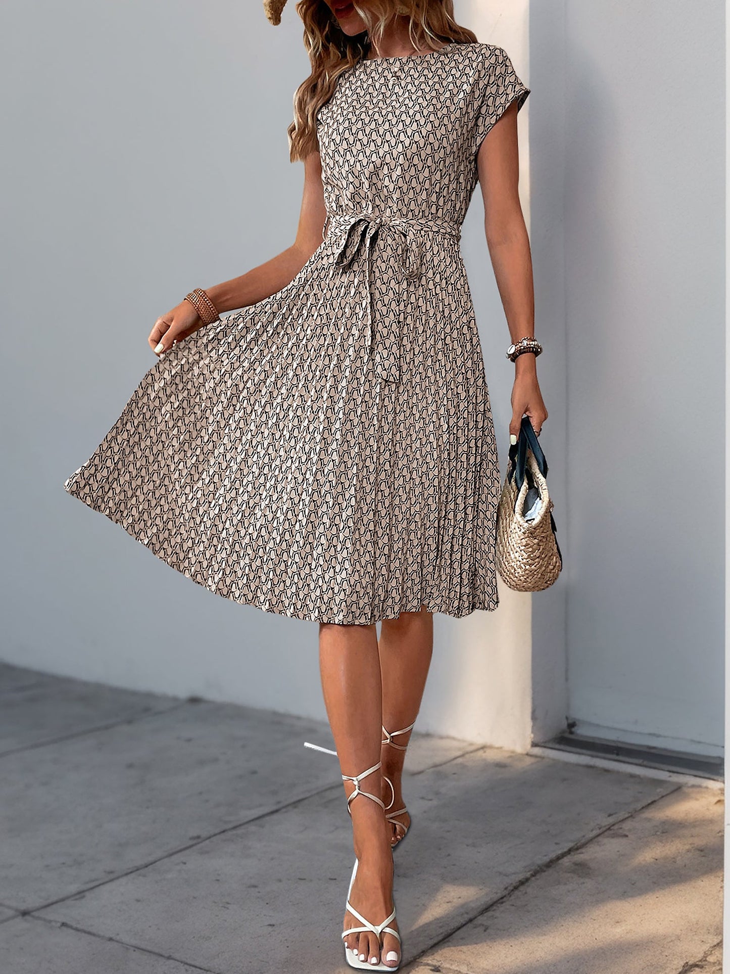 Khaki - Woman wearing a floral print midi dress featuring cap sleeves, a tie waist sash, and a finely pleated skirt.