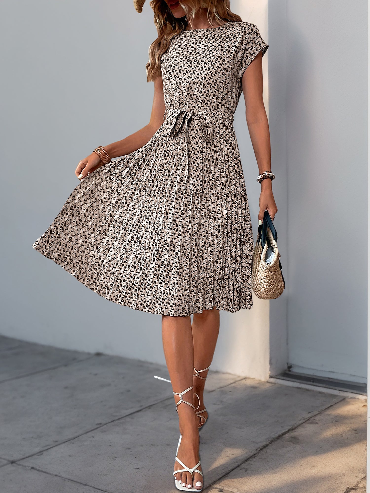Khaki - Woman wearing a floral print midi dress featuring cap sleeves, a tie waist sash, and a finely pleated skirt.