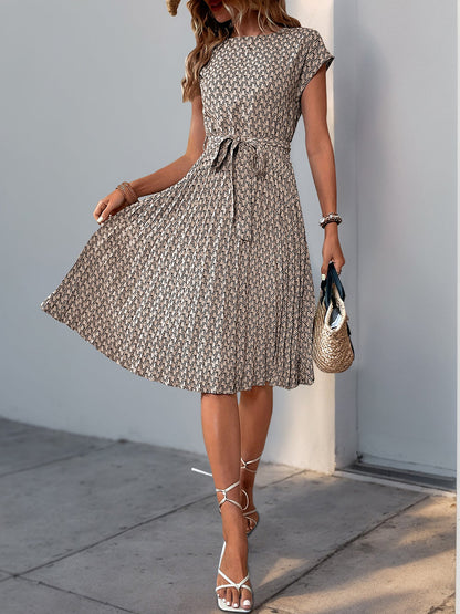 Khaki - Woman wearing a floral print midi dress featuring cap sleeves, a tie waist sash, and a finely pleated skirt.