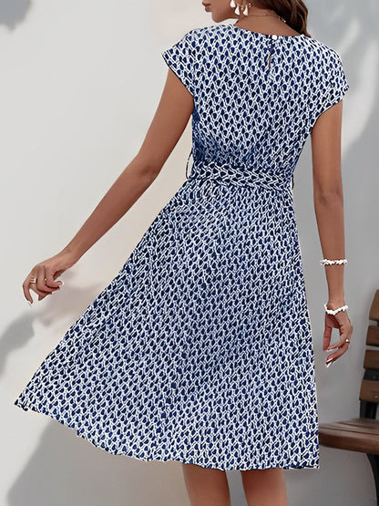 Navy Blue - Woman wearing a floral print midi dress featuring cap sleeves, a tie waist sash, and a finely pleated skirt.