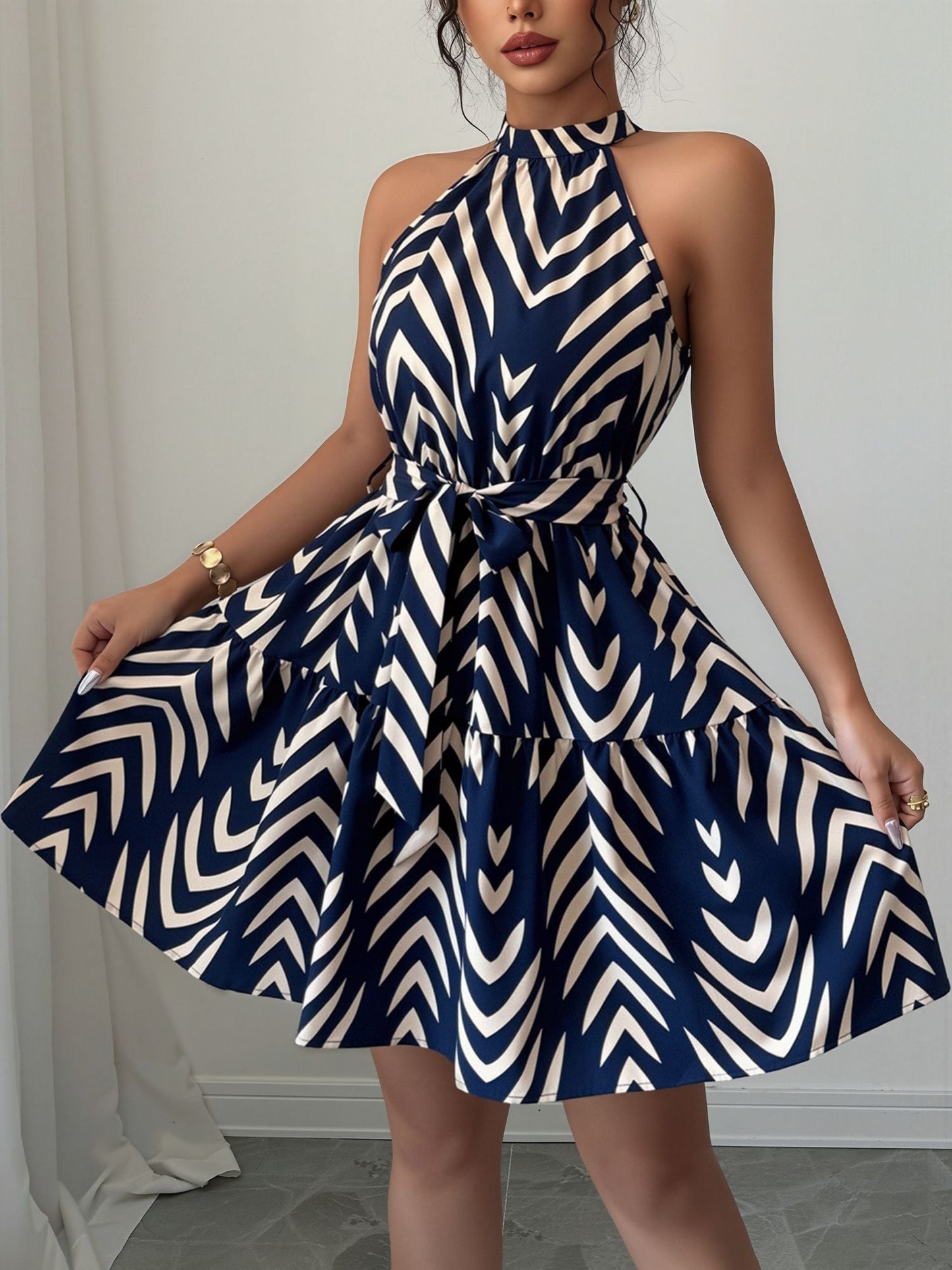 Blue - Woman wearing a sleeveless halter neck mini dress with a geometric pattern, featuring a tie waist and tiered skirt