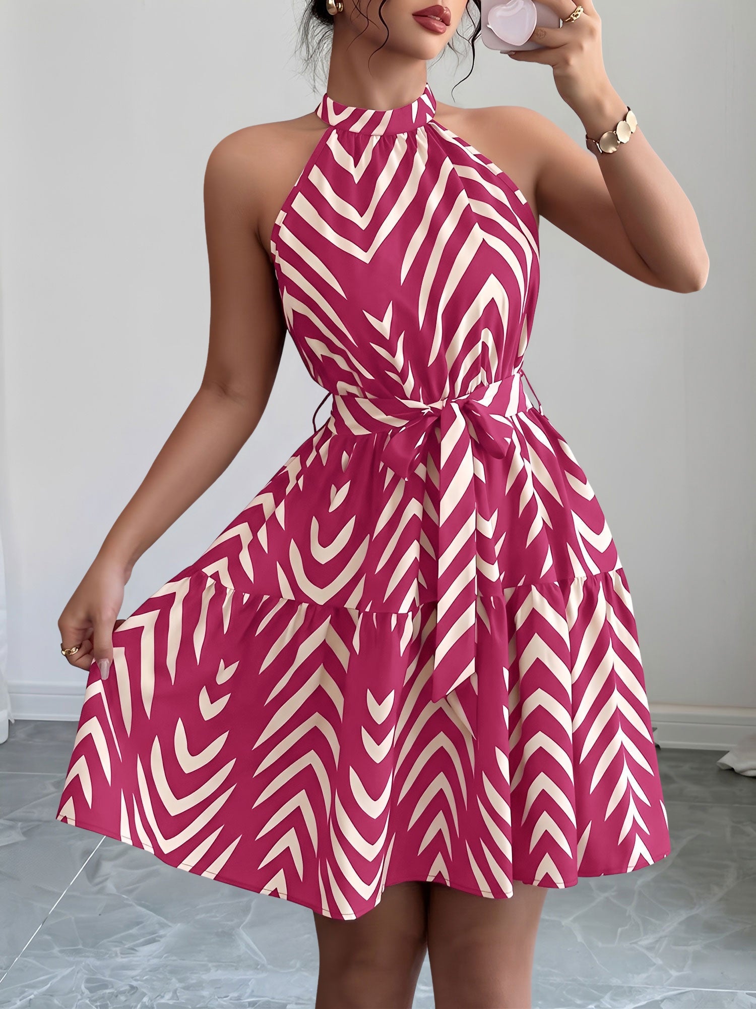 Rose Red - Woman wearing a sleeveless halter neck mini dress with a geometric pattern, featuring a tie waist and tiered skirt
