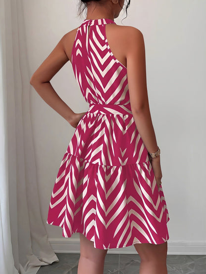 Rose Red - Woman wearing a sleeveless halter neck mini dress with a geometric pattern, featuring a tie waist and tiered skirt