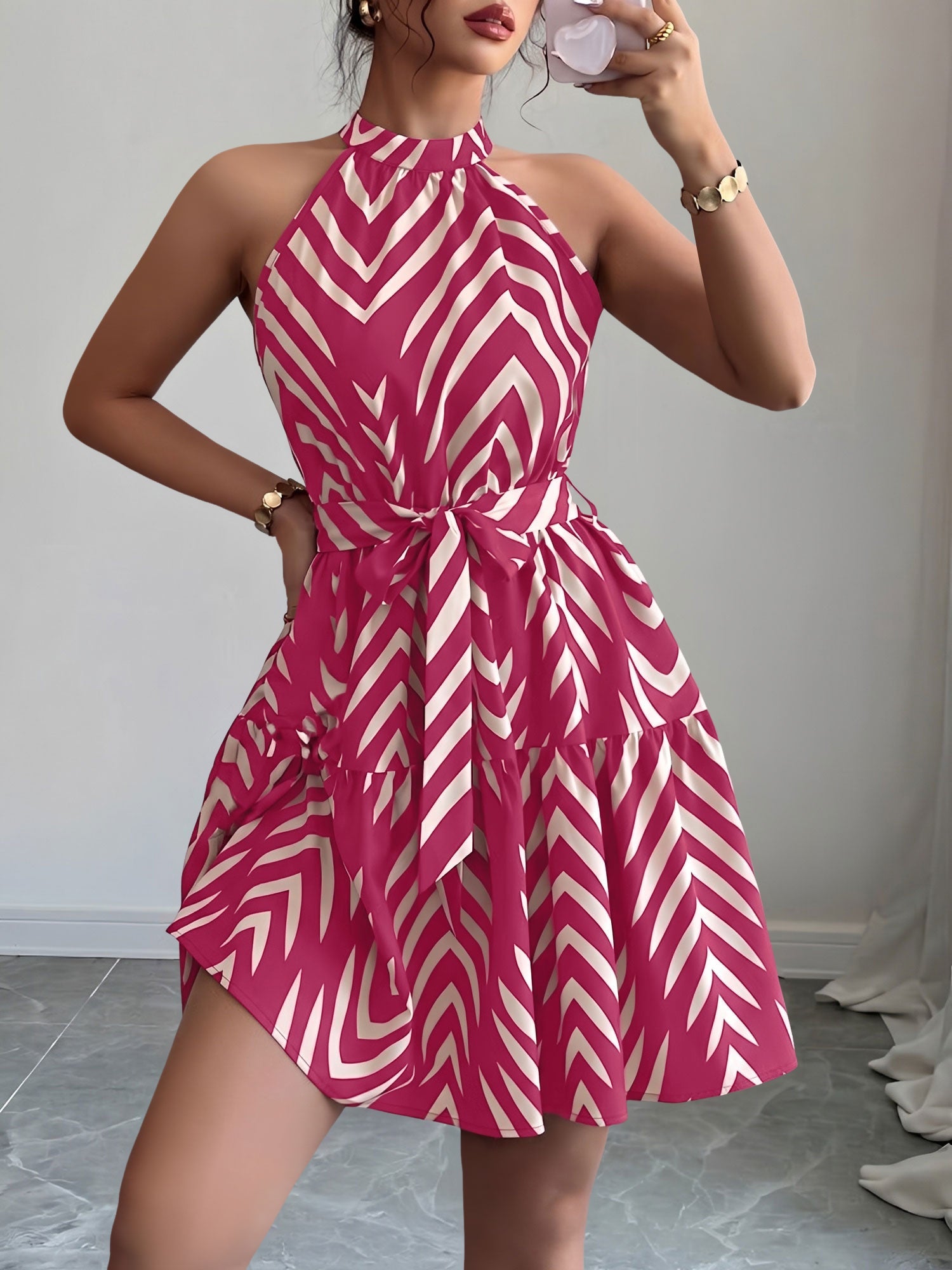 Rose Red - Woman wearing a sleeveless halter neck mini dress with a geometric pattern, featuring a tie waist and tiered skirt