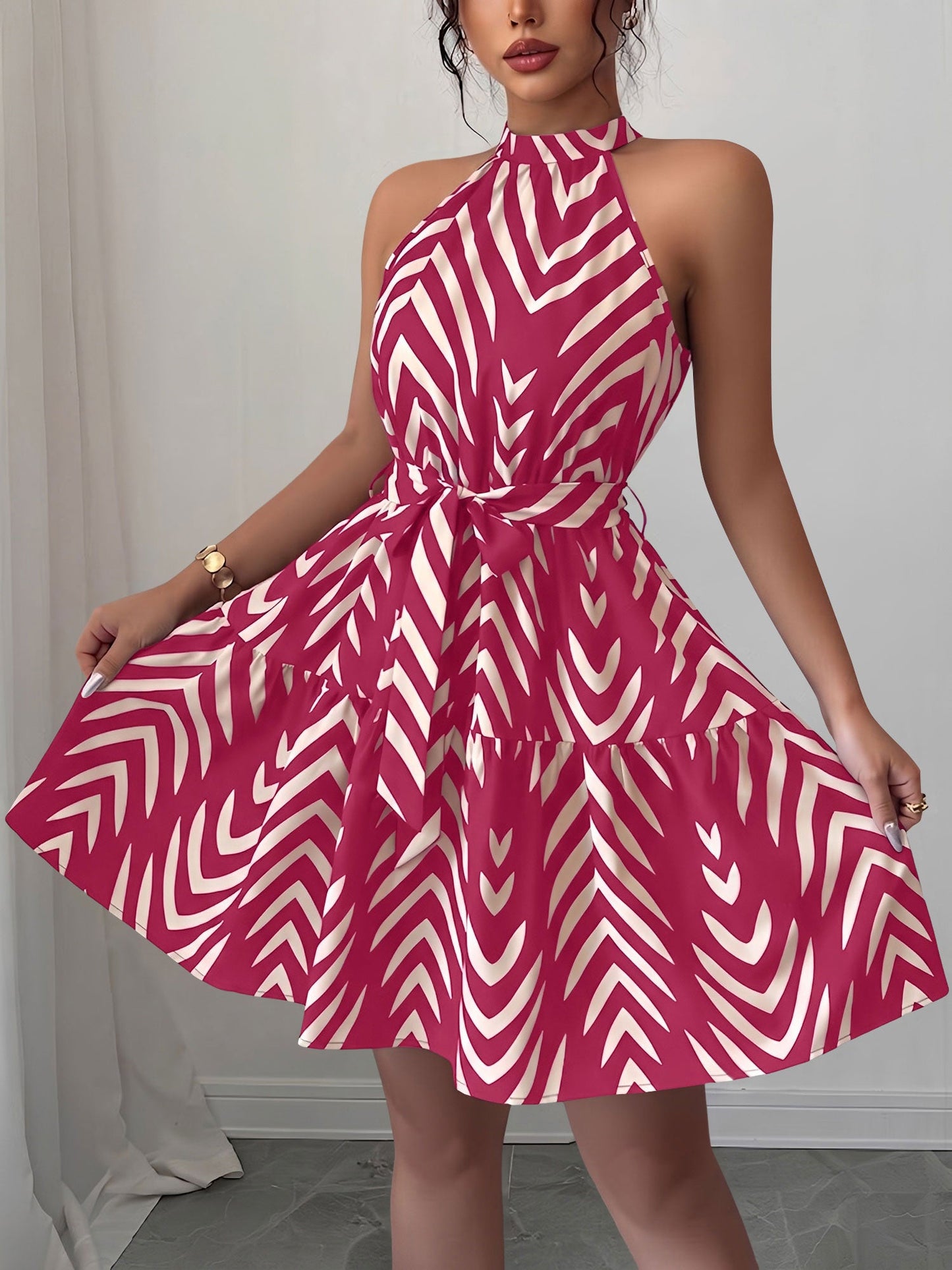 Rose Red - Woman wearing a sleeveless halter neck mini dress with a geometric pattern, featuring a tie waist and tiered skirt