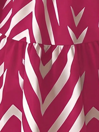 Rose Red - Woman wearing a sleeveless halter neck mini dress with a geometric pattern, featuring a tie waist and tiered skirt