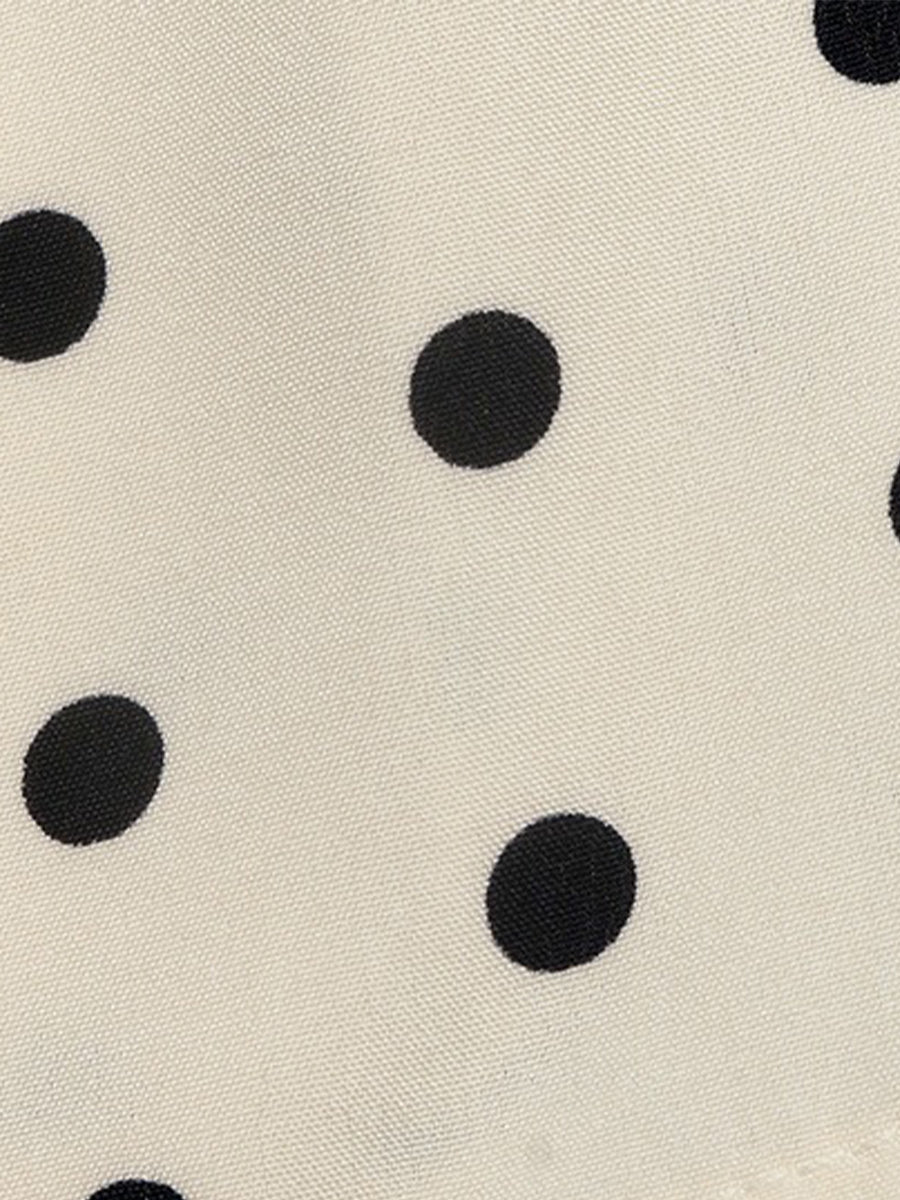 Apricot - Woman modeling a sleeveless halter neck mini dress with a polka dot print and blouson top