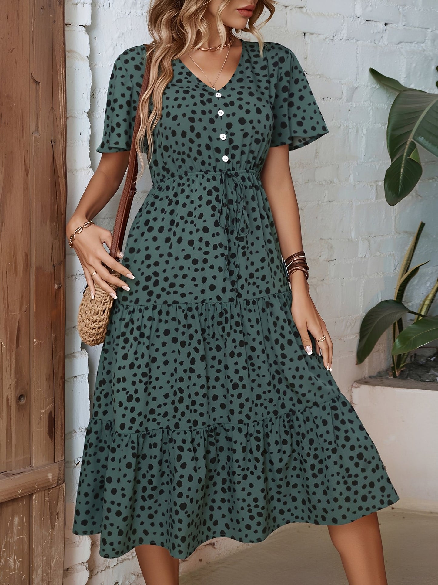 Dark Green - Woman wearing a polka dot V-neck midi dress with a tie waist and a tiered skirt featuring side pockets.