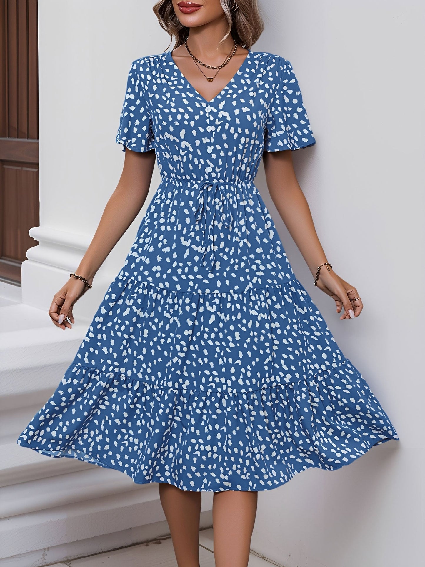 Blue - Woman wearing a polka dot V-neck midi dress with a tie waist and a tiered skirt featuring side pockets.