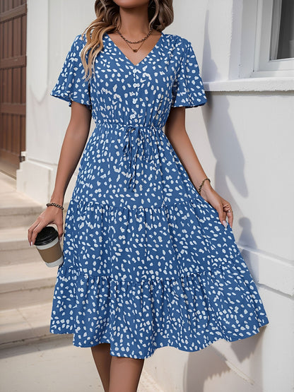 Blue - Woman wearing a polka dot V-neck midi dress with a tie waist and a tiered skirt featuring side pockets.