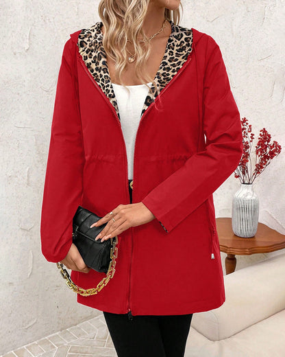 Black Polka - Women's mid-length red zip-up anorak jacket worn open to reveal a bold leopard print interior lining, featuring front pockets and an internal drawstring waist.