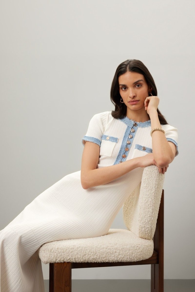White - Full-length view of a woman wearing a short-sleeved, cream ribbed knit midi dress featuring a blue frayed trim on the crew neck, button placket, and chest pockets.