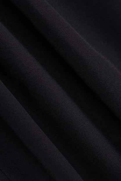 A woman models a black structured mini blazer dress featuring a high mock neck, a deep plunging keyhole cutout, extended cap sleeves, and a flared A-line skirt with flap pockets.