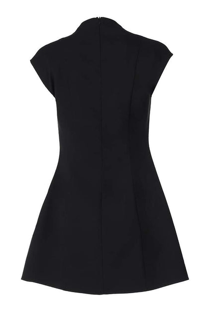 A woman models a black structured mini blazer dress featuring a high mock neck, a deep plunging keyhole cutout, extended cap sleeves, and a flared A-line skirt with flap pockets.
