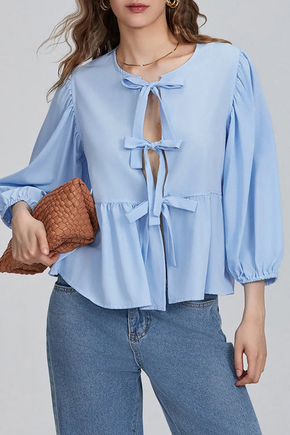Woman wearing white cotton tie-front peplum blouse and jeans