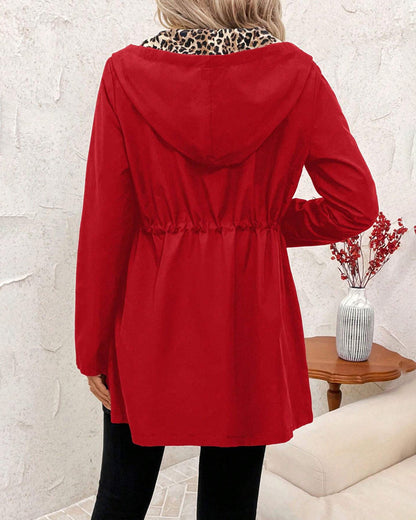 Black Polka - Women's mid-length red zip-up anorak jacket worn open to reveal a bold leopard print interior lining, featuring front pockets and an internal drawstring waist.