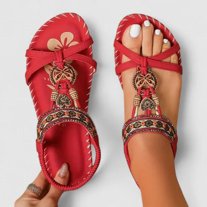 Toledo Red - Flat open-toe sandals featuring intricate beaded medallions, contrast stitching along the sole, and an elasticized slingback strap.