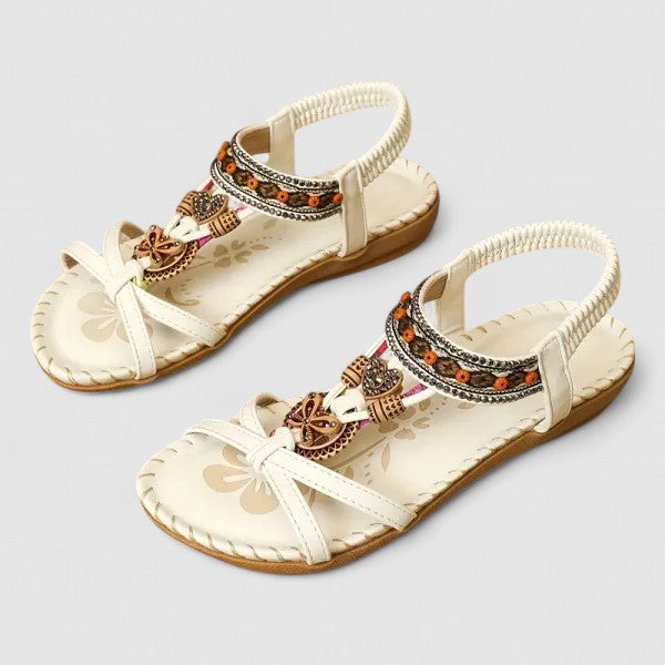 White Athena - Flat open-toe sandals featuring intricate beaded medallions, contrast stitching along the sole, and an elasticized slingback strap.