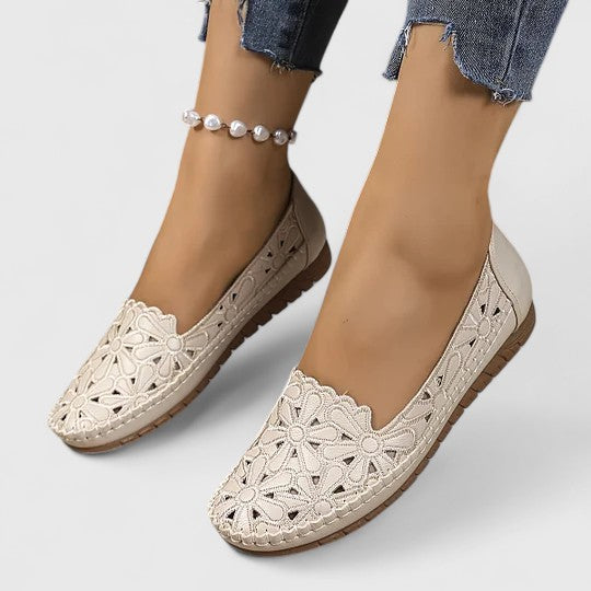 Beige - Women's slip-on loafers featuring a faux-leather upper with intricate floral cutouts and a flat, textured sole.